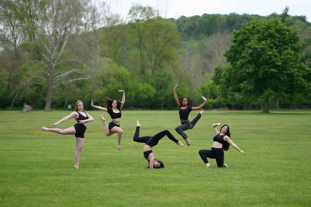 Dancers posing outdoors on a green hillside