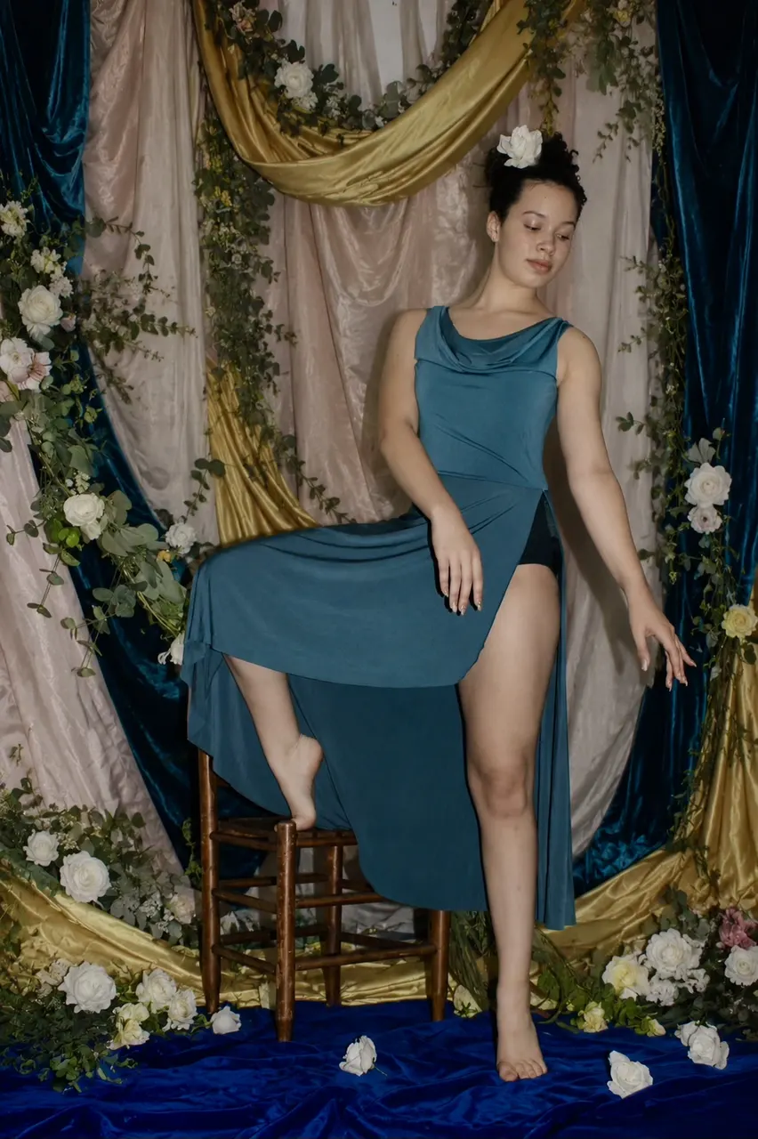 A dancer in a teal dress posing among flowers