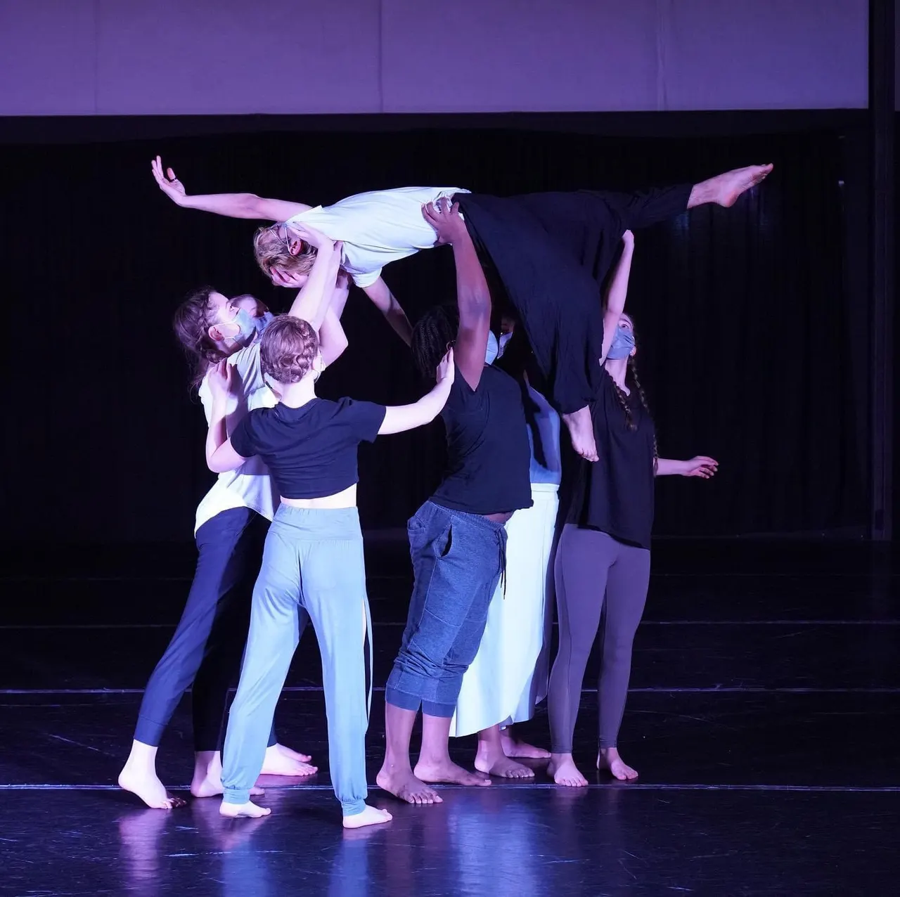 Dancers lifting one of their group high on stage