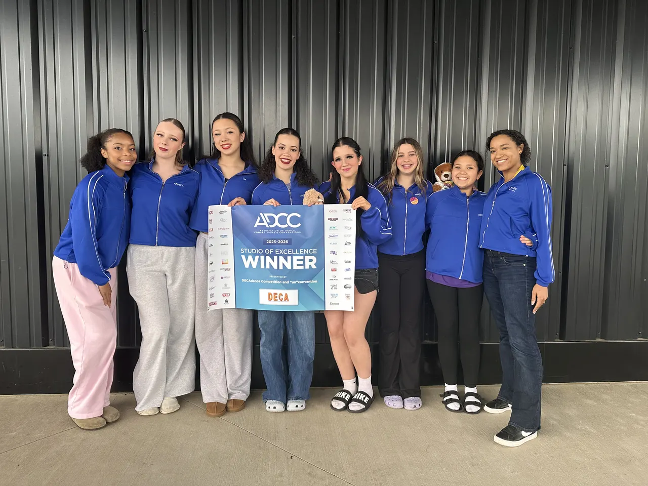 Project C company dancers holding a competition winner banner